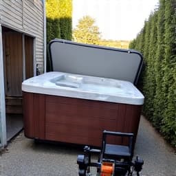 Professionals carefully maneuvering spa components through a narrow path in a Marana backyard during removal.